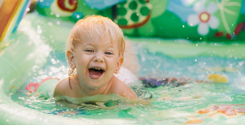 child plays in the pool. Little girl in the pool, smiling child.